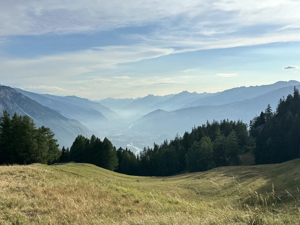 Vue sur une prairie, la vallée et la chaîne de montagnes